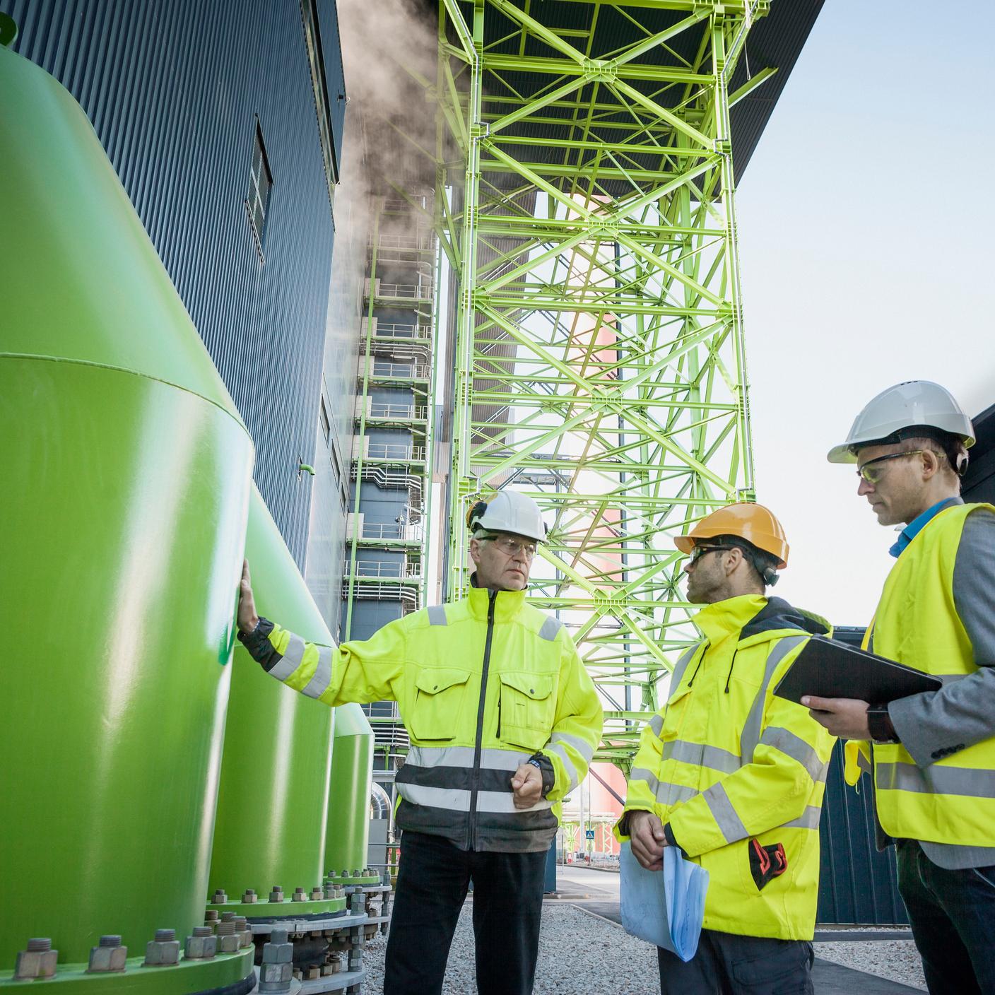 PAS 5420 - Engineers using digital tablet at sunny wind turbine power plant