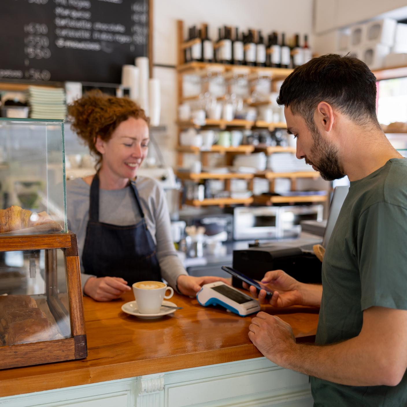 A man making a mobile payment at a cafe using his cell phone