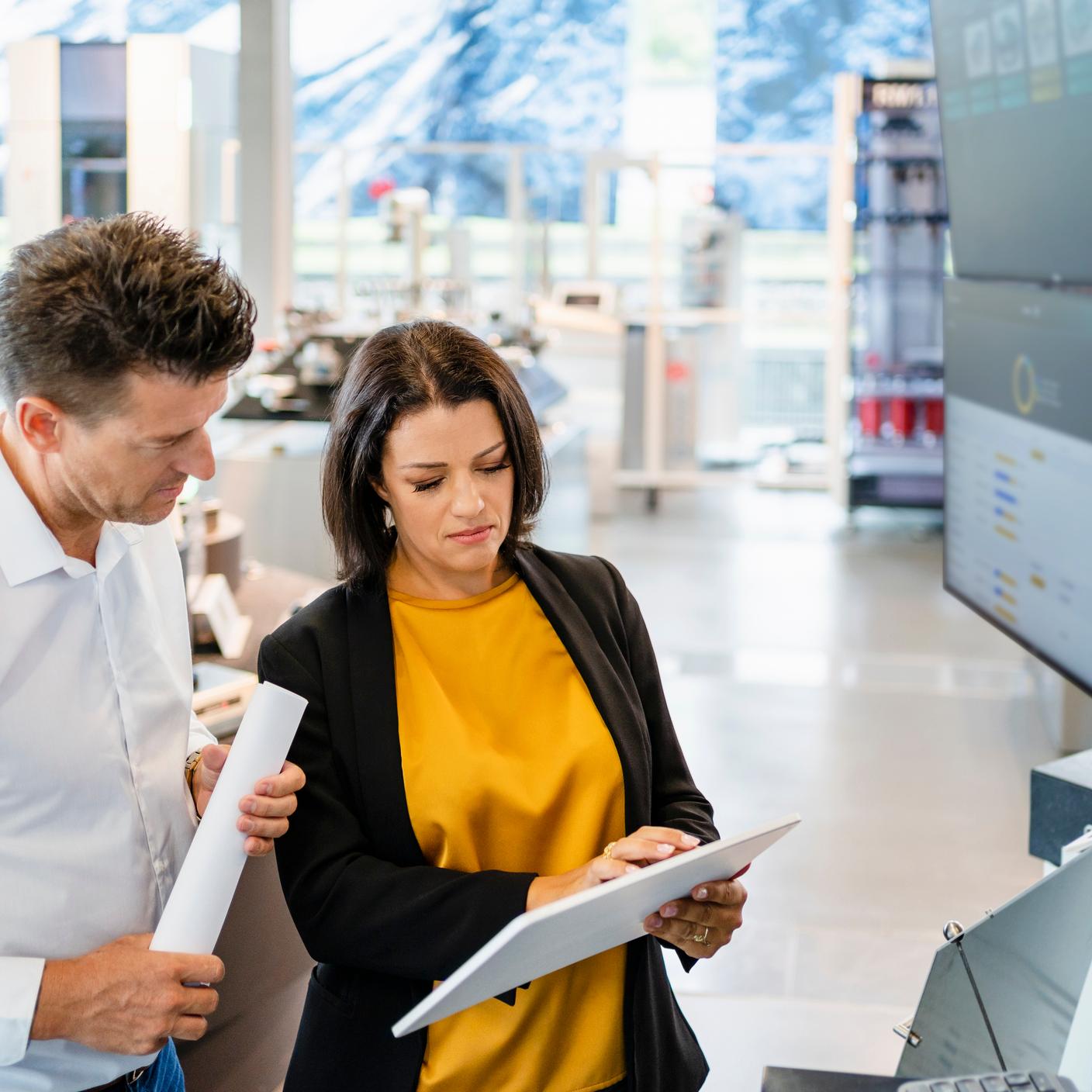 Businesswoman using tablet PC standing by colleague in industry