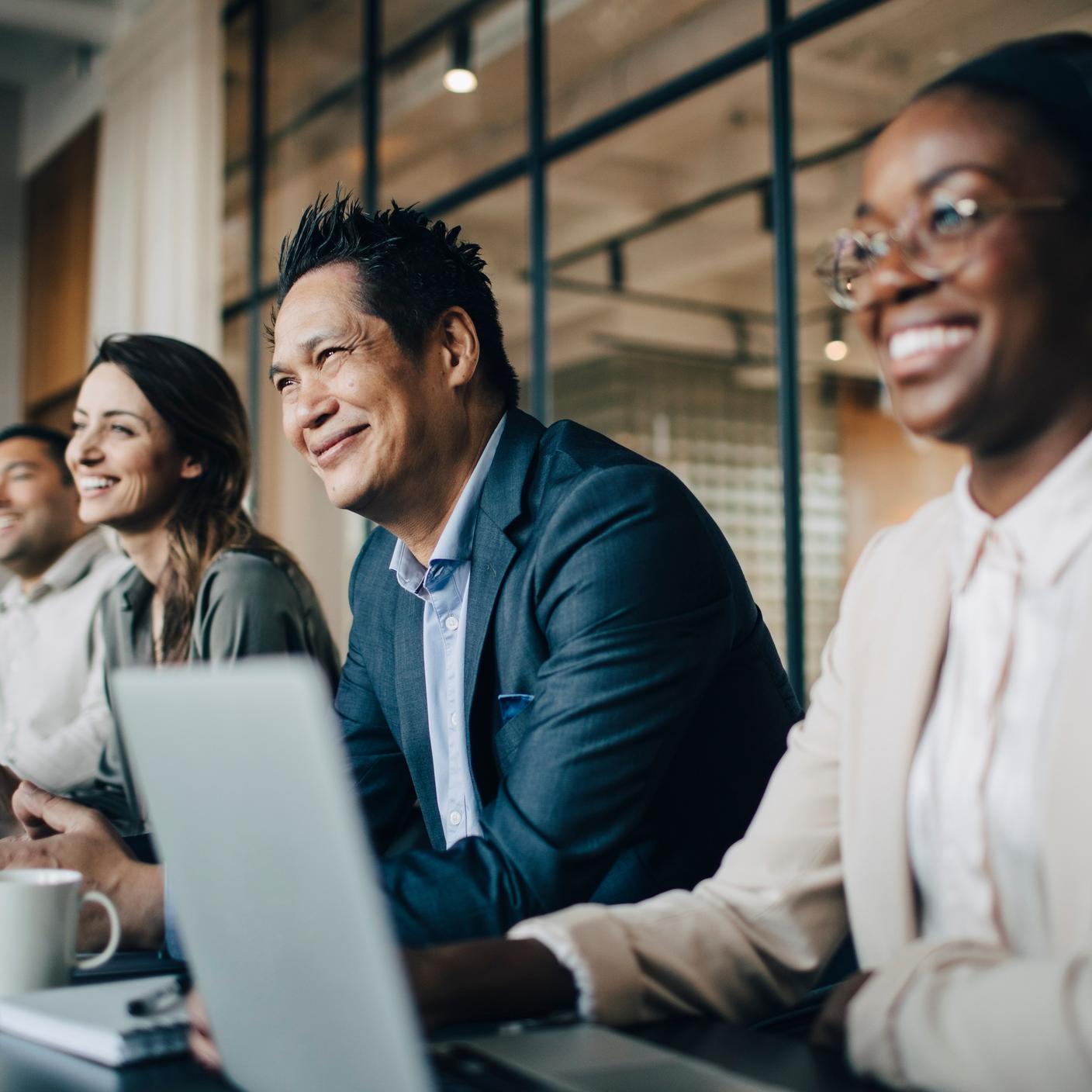 PAS 1948 - Diversity, equality and inclusion in the workplace - Smiling multiracial business colleagues discussing in meeting at office