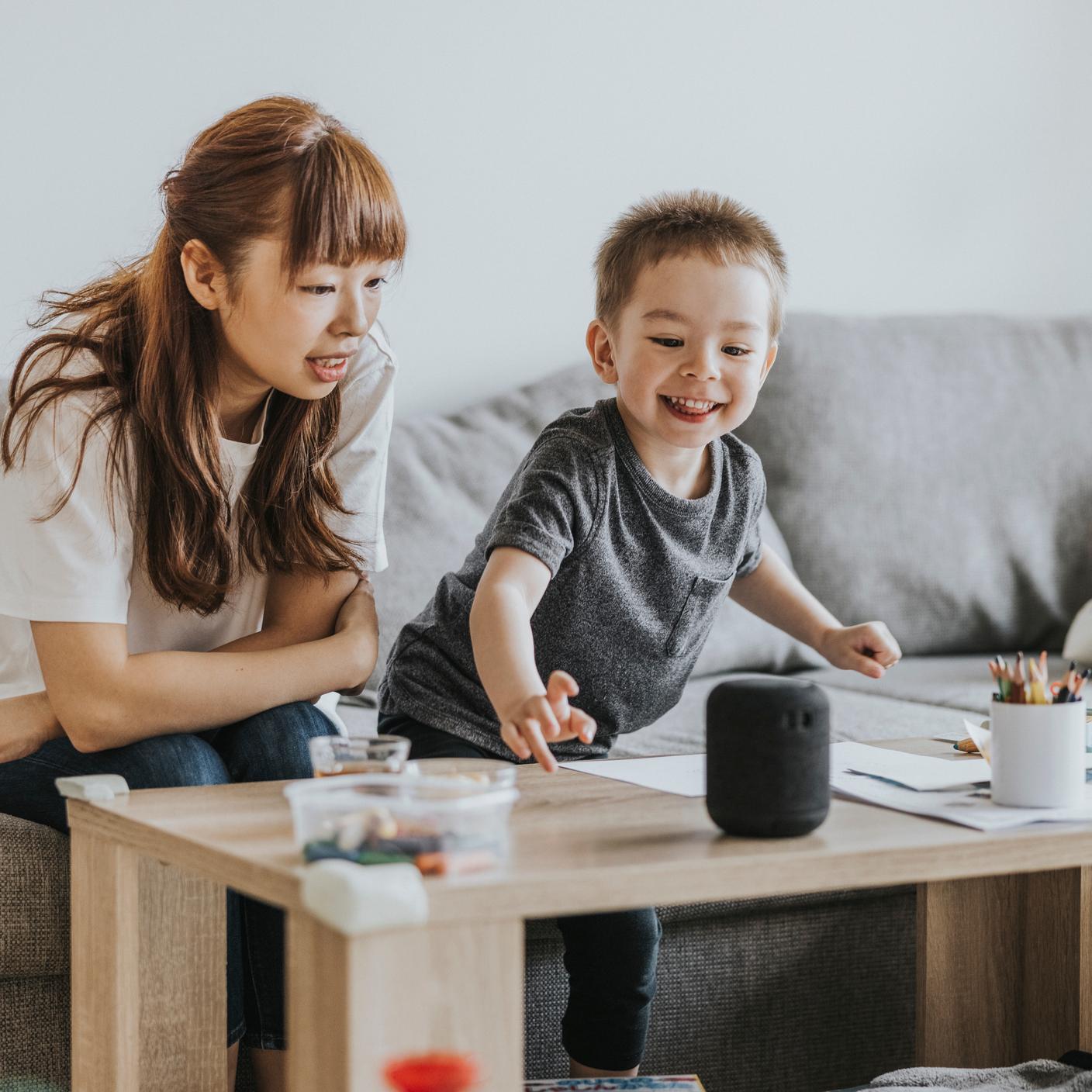 Mother teaching son to use mobile app while operating dishwasher in kitchen at home