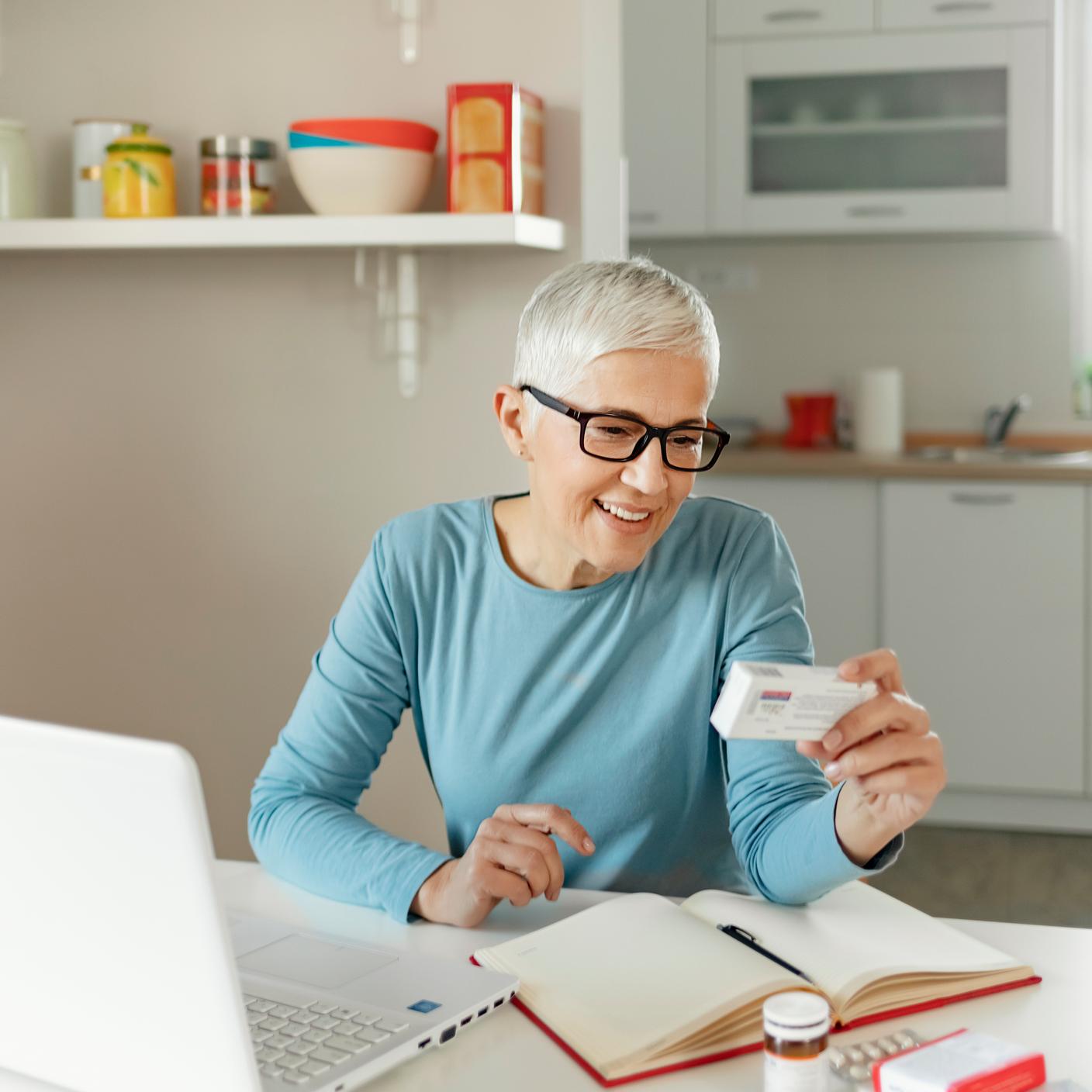 Mature lady reading pills instructions on laptop