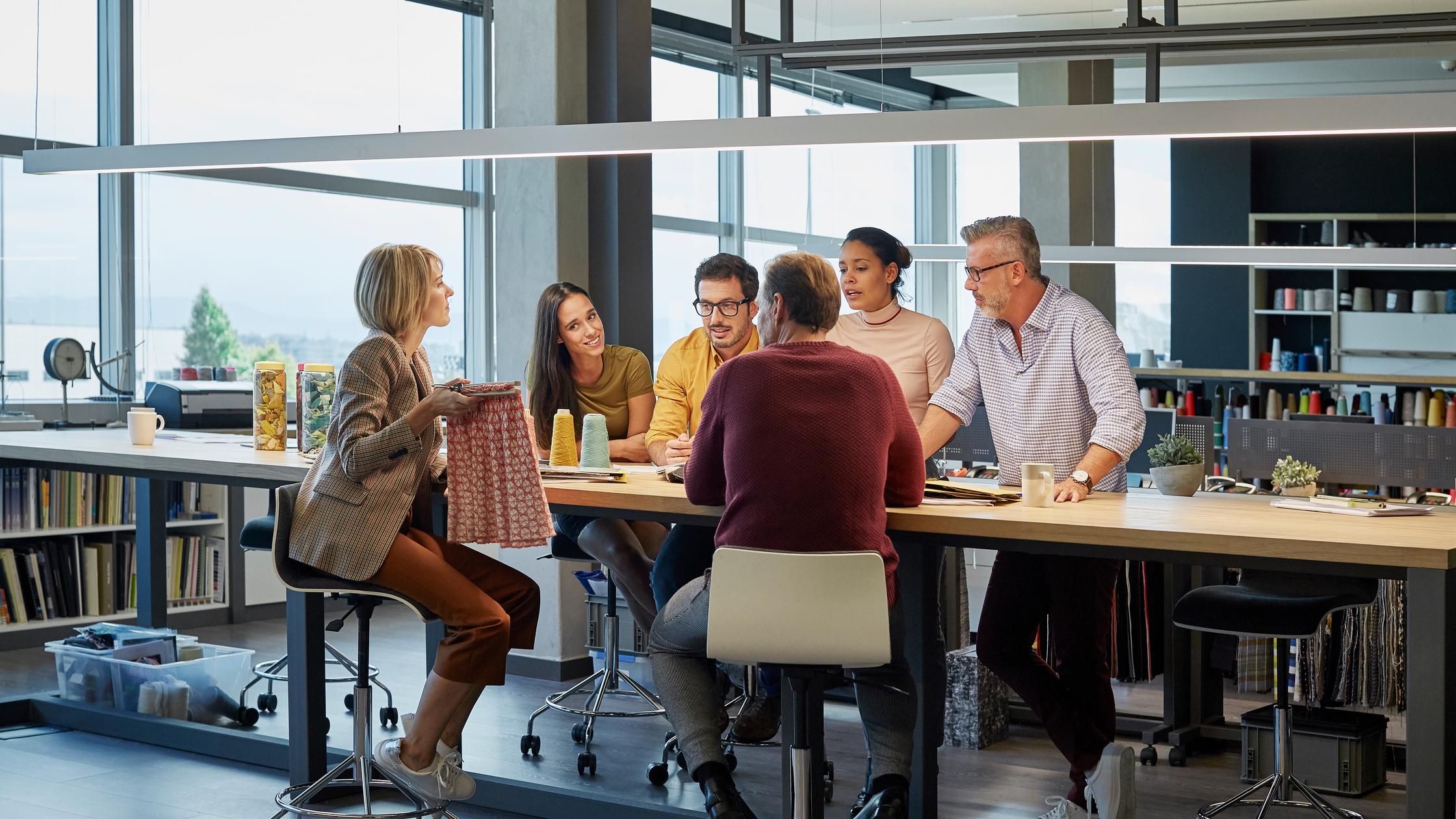 Business people discussing over fabric at conference table